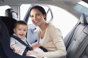 Mother securing her baby in the car seat in her car